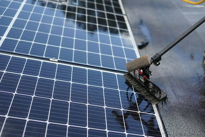 Cleaning solar panels with a long-handled brush