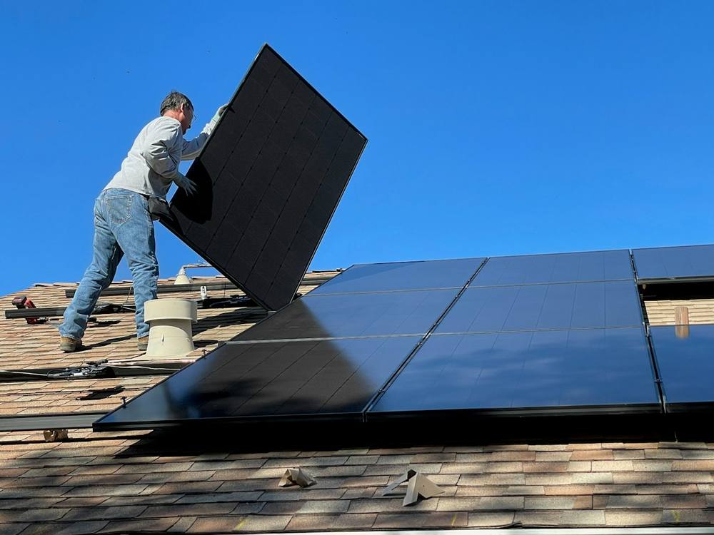 Technician installing a solar panel on a roof